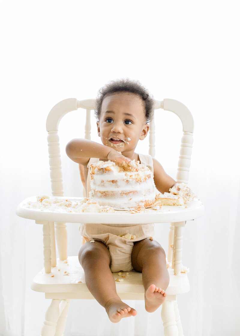 A baby sits in high chair for milestone first birthday and a cake smash