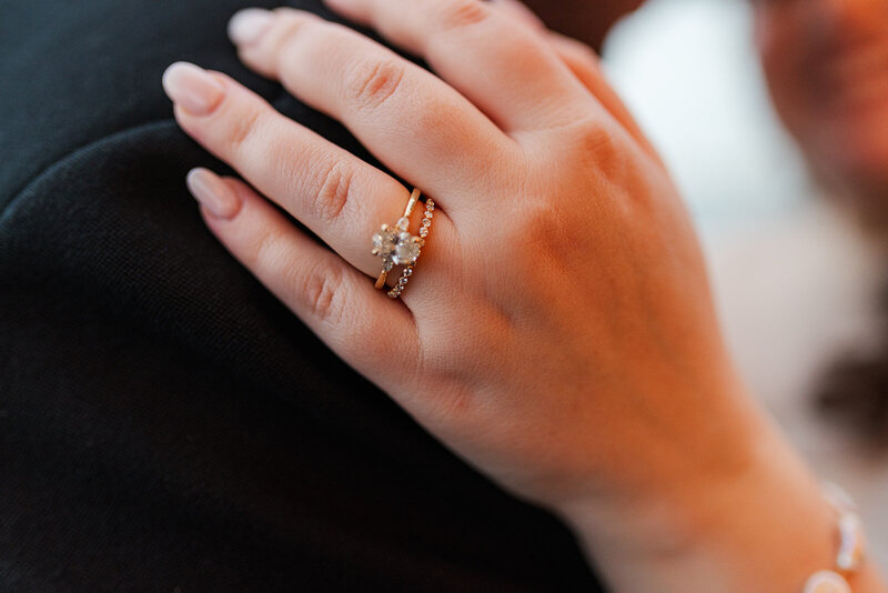 Close up image of the wedding rings on the Jewish bride's left hand resting on the shoulder of her Scottish groom 