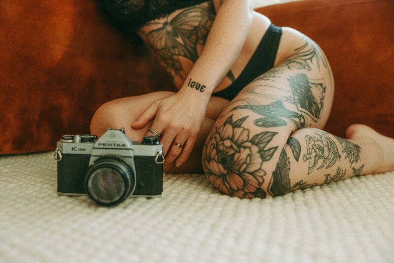 Tattooed Woman Kneeling With Vintage Camera on Carpet