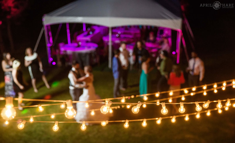 String lights add ambient light to dark outdoor wedding reception dancing on the green grassy lawn at Estes Park Condos