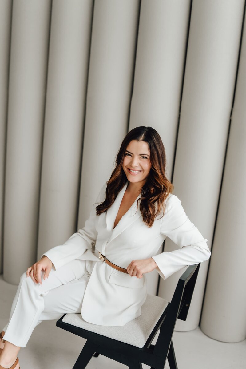 Fotografin im Atelier, die vor dem schwarzen Hintergrund sitzt