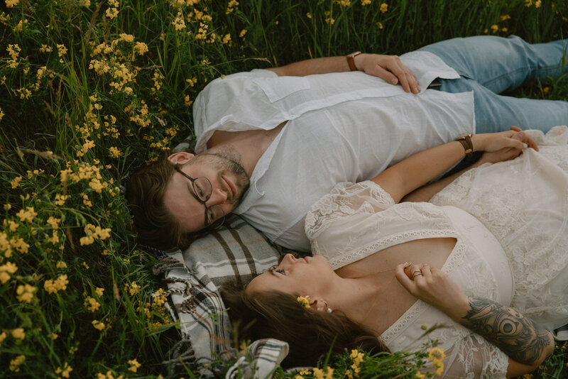 An engagement photoshoot of a couple laying in the flower fields at the floodway while looking at each other, captured by Longpine Photography.