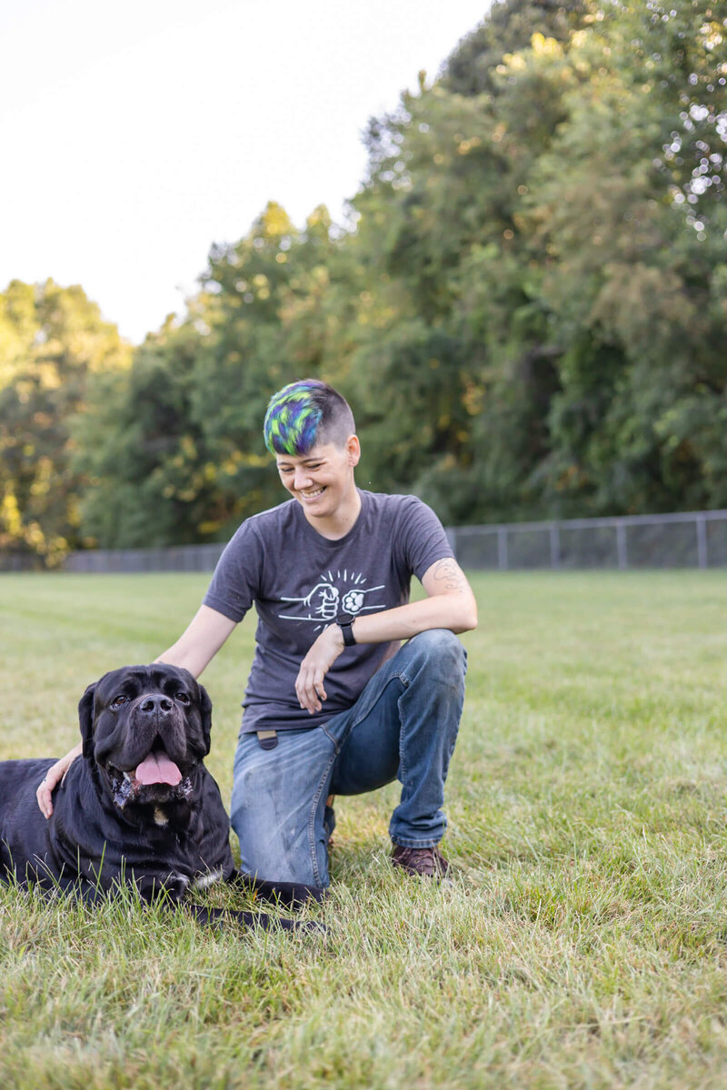 Dog trainer looks down at her Cane Corso  who is looking at the camera.