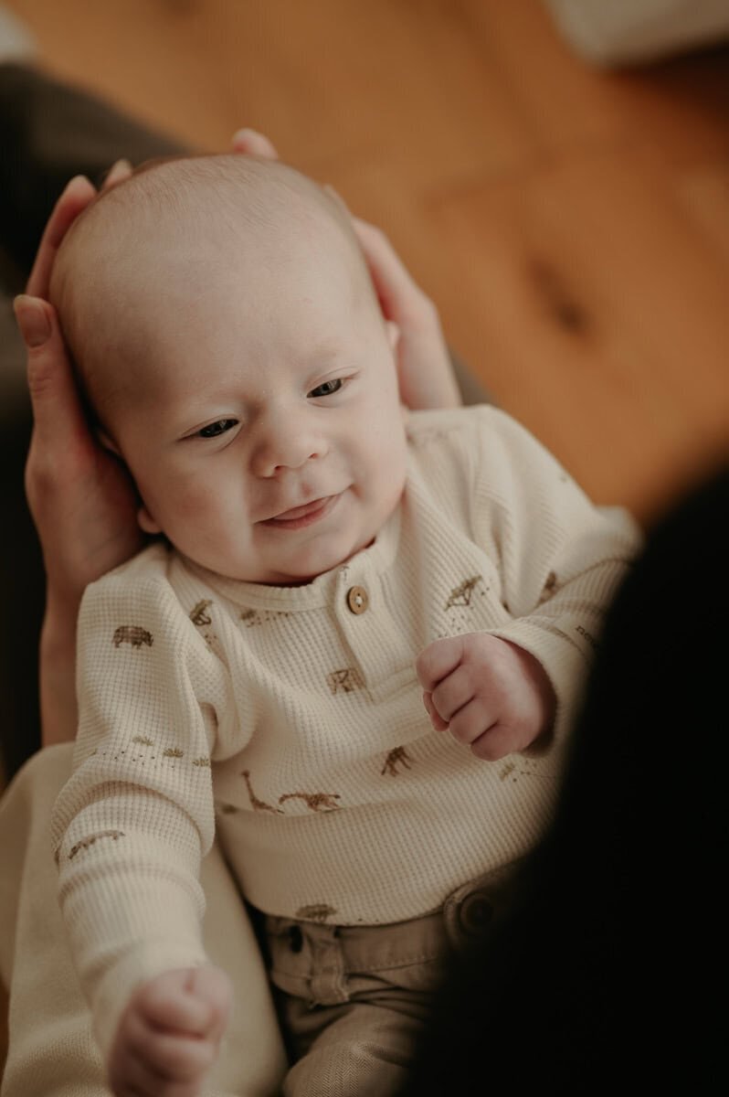 Bebis ligger i knä på sin mamma och ler.