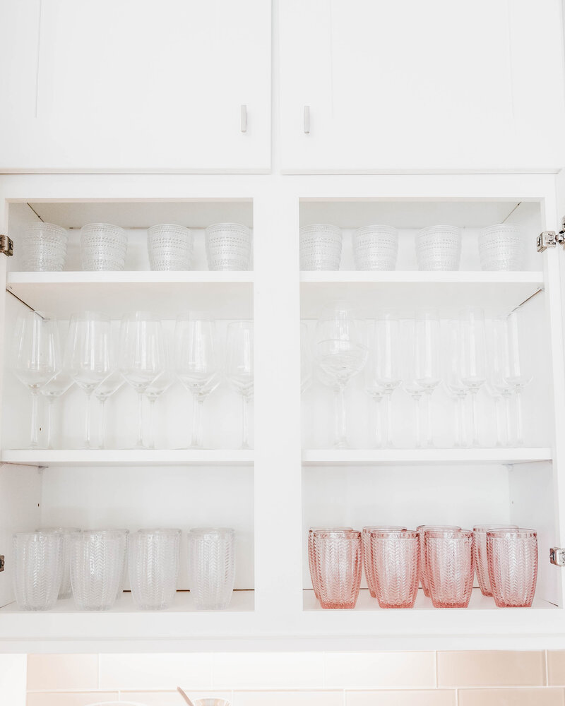 A kitchen cabinet featuring organized glassware