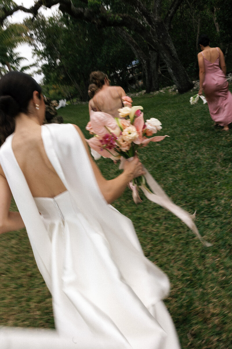 bride and groom kissing while bridal party walks behind them by naples florida wedding photographer