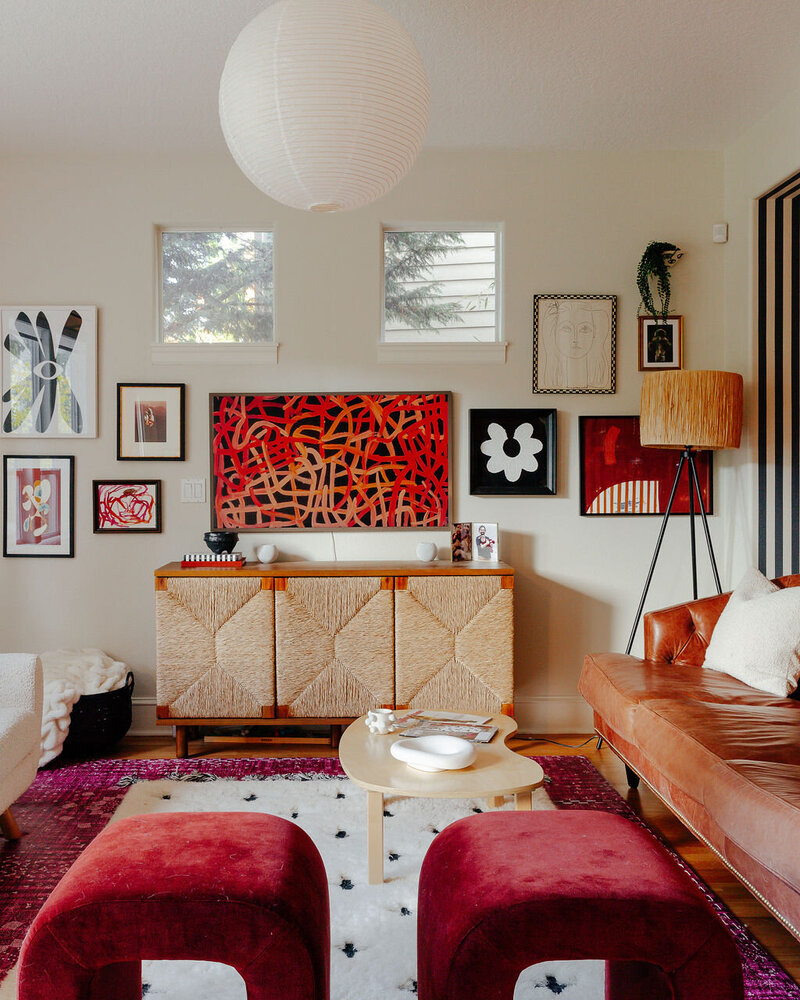 A seating area with a credenza, rugs on the floor and colorful artwork on the wall, representing a maximalist interior design.