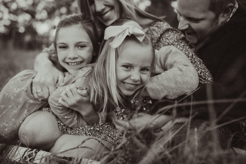 A young girl laughs while her family squeezes and tickles her while sitting on a blanket at The Vine Photography Venue in Acworth. 