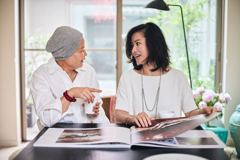 Thara and her client sitting at the table and browsing through a large book with blue designs