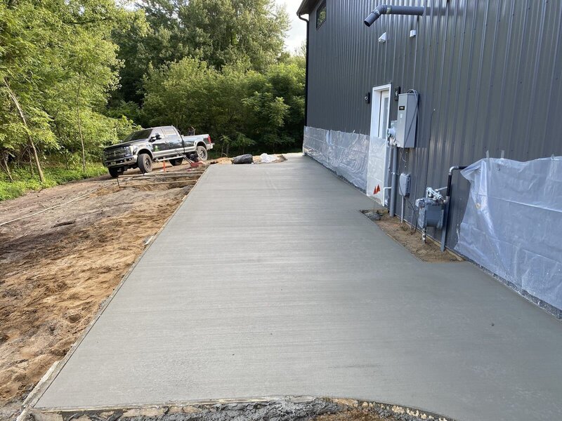 New concrete driveway along a dark metal building in Elkhart, IN