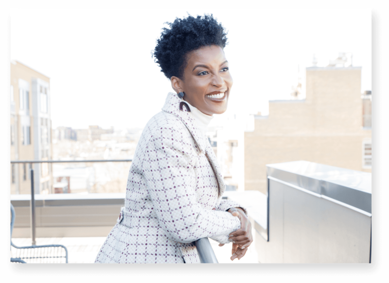 Woman with short curly hair wearing a coat outsite looking out a veranda