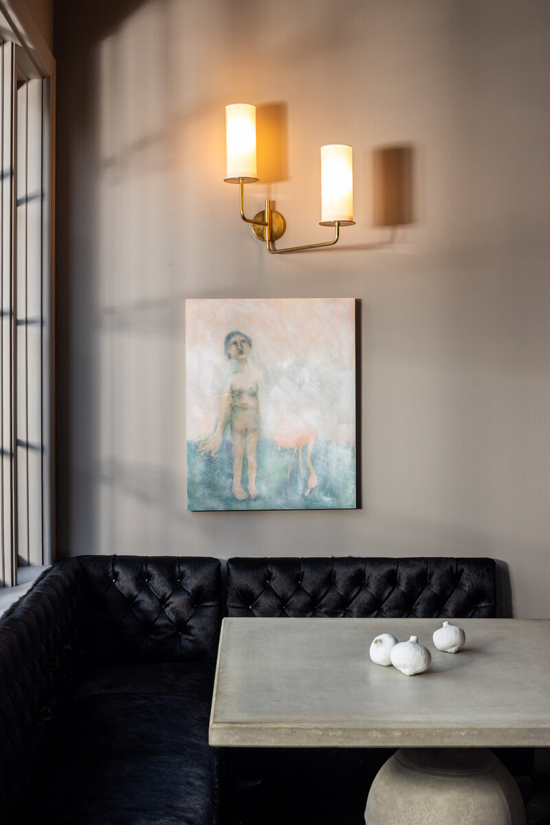 Interior brand photography of a dining nook with black leather seating and abstract art.