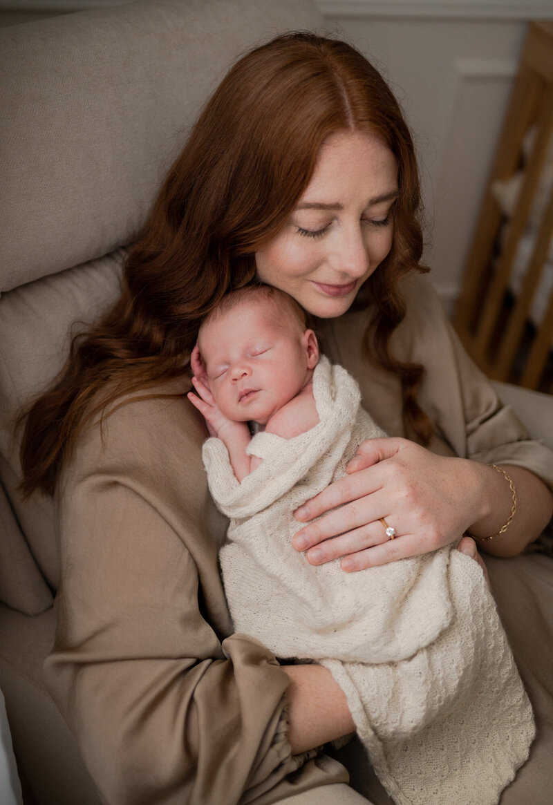 Mother with red hair, holding her sleeping newborn baby