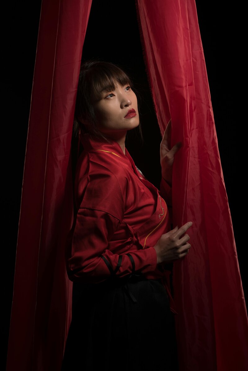 woman standing by red curtain