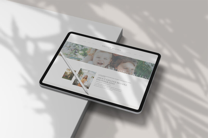 A tablet with a stylus rests on a white surface, displaying a photography website featuring children’s portraits and an about section—an elegant showcase of web design and branding. Soft leaf shadows add charm to the custom brand and website design.