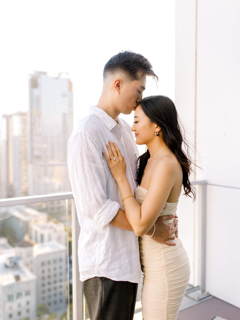 rooftop engagement photo of groom kissing bride on the forehead in los angeles