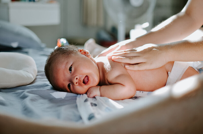 Photo d'un bébé sur le ventre souriant se faisant masser le dos