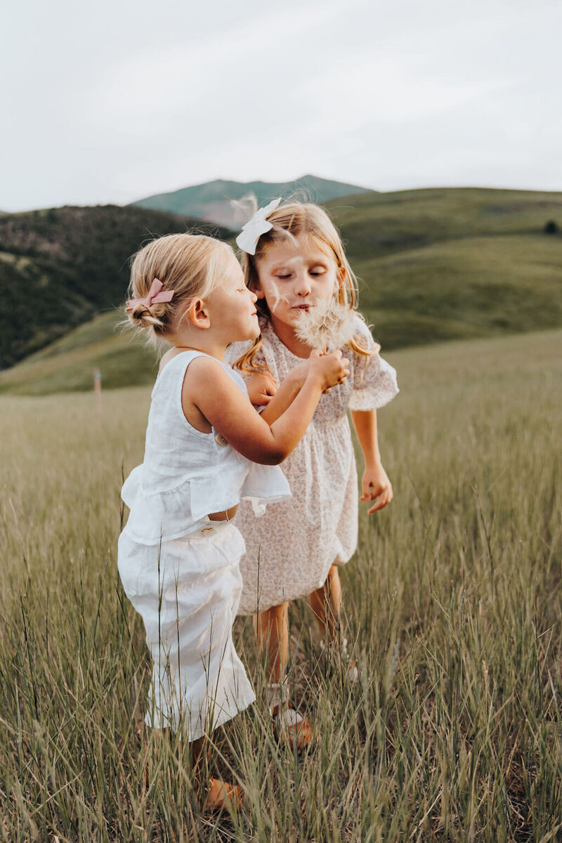 Two girls flower picking in open field