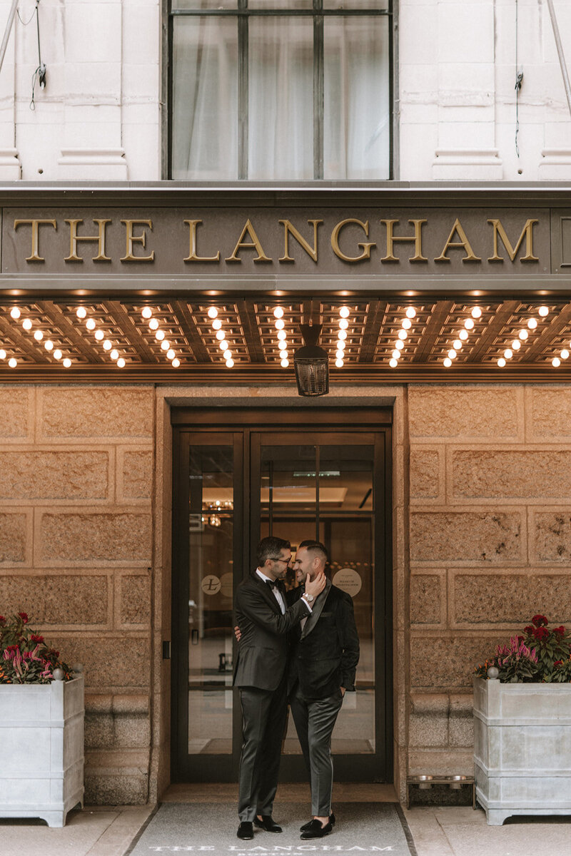 Two grooms posing in front of venue