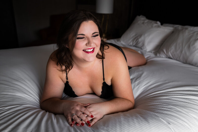 Boudoir photo of woman in black lingerie smiling in bed, Missoula, MT