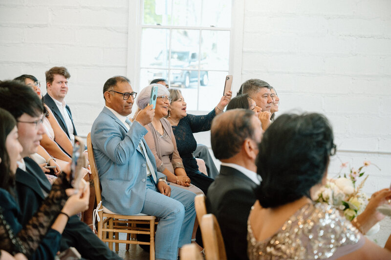 wedding guest sitting and taking pictures of the ceremony