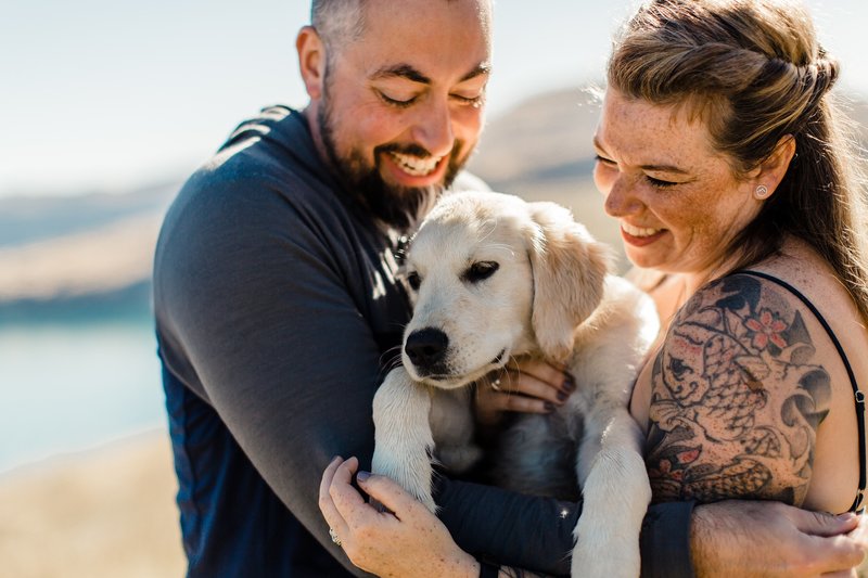 man and woman with golden retriever puppy in their arms