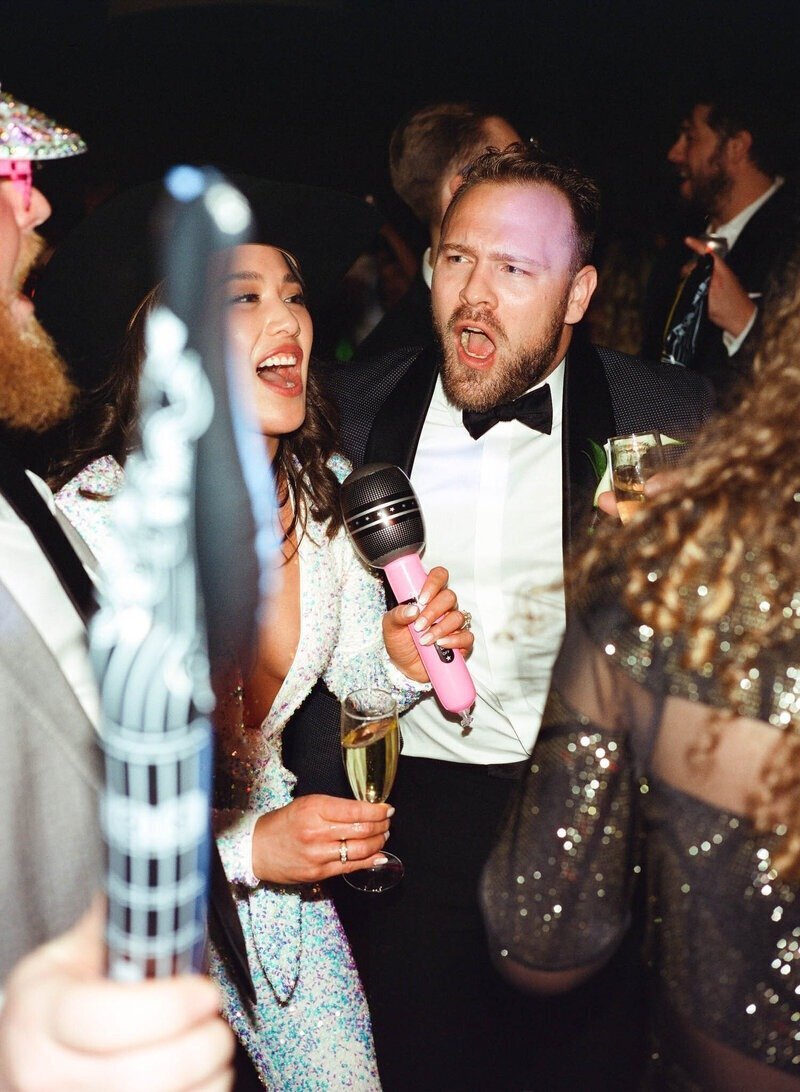 bride and groom singing on wedding day dance floor holding pink microphone shot by minnesota wedding photographer tom thornton photography