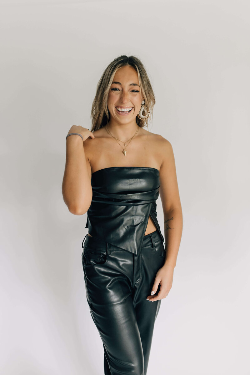 Headshot of certified hair stylist with blond hair extensions smiling wearing black