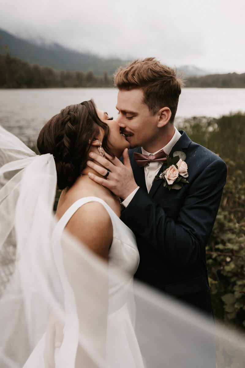 Couple kiss at their lakefront wedding