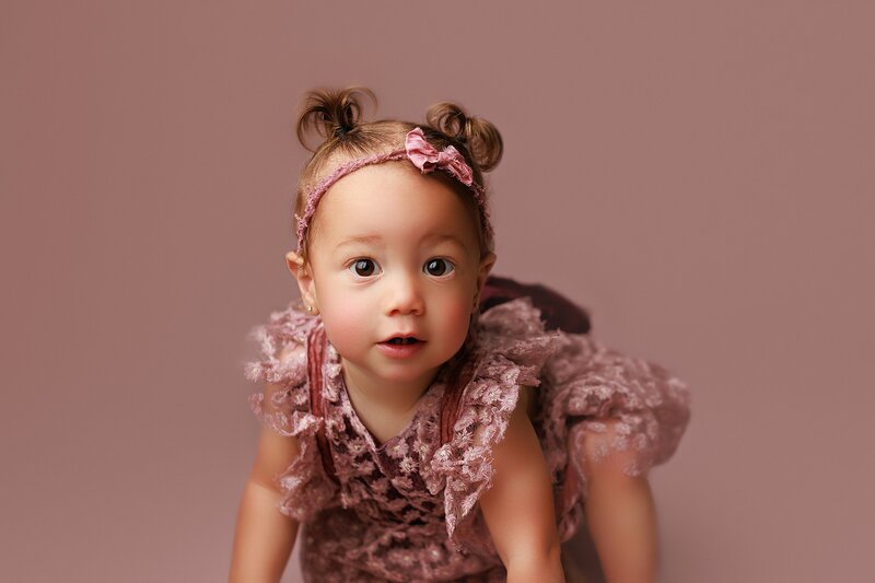 Curious baby making silly face during playful milestone session