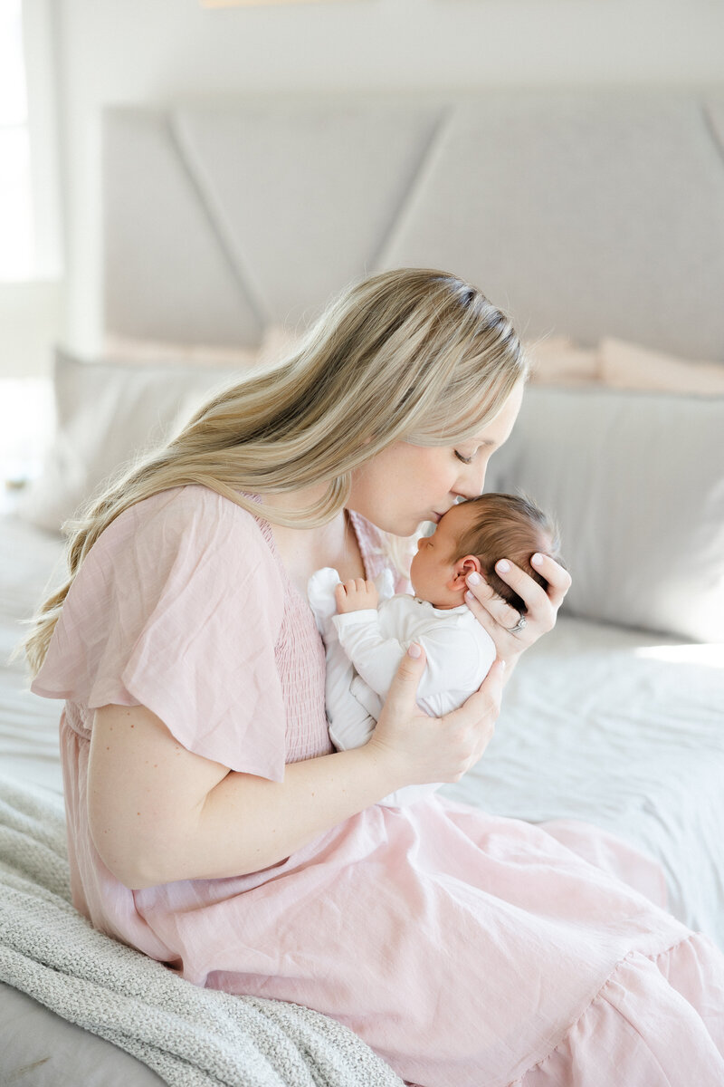 mom kissing newborn baby's forehead during an in home lifestyle newborn session