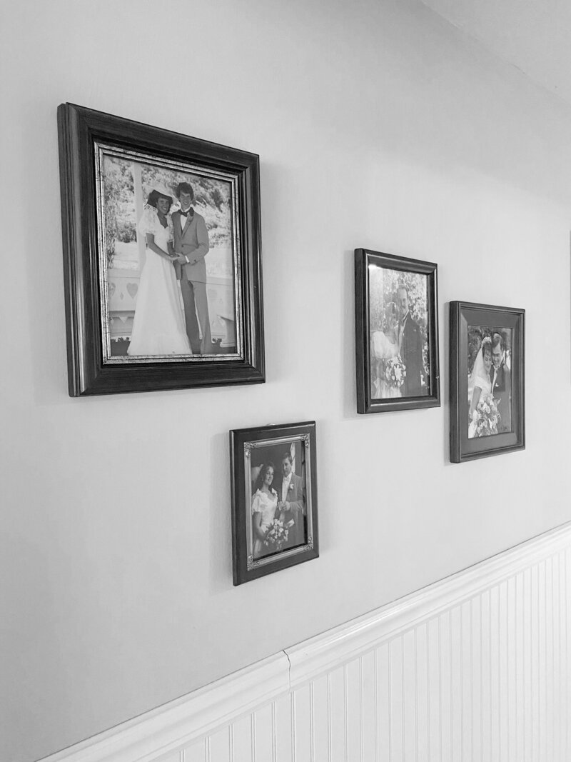 Black and white photo of a hallway lined with wedding photos from my grandparent and parents
