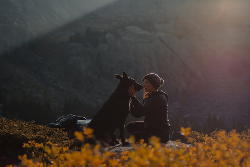 Authentic adventure portrait of a woman and dog in a rustic Black Hills setting, captured by Ashley Rae.