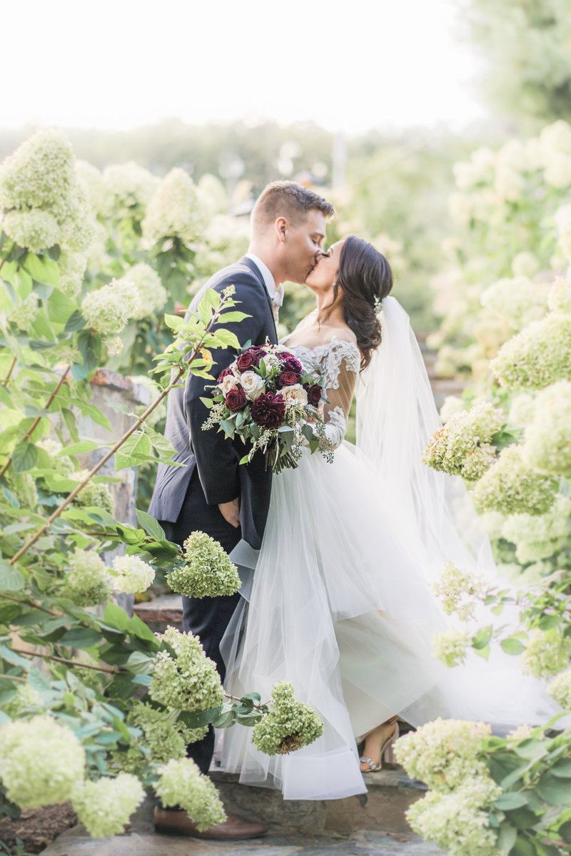 Bride and groom hugging with joy in front of a horse and carriage.