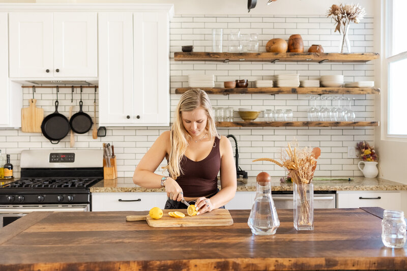 Woman in a bright white styled kitchen cutting lemons for her Bay Area Brand photography photoshoot.