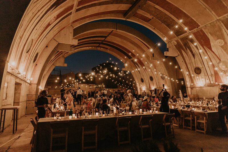 A bride and groom with their hands up walking through a tunnel of their wedding guests.