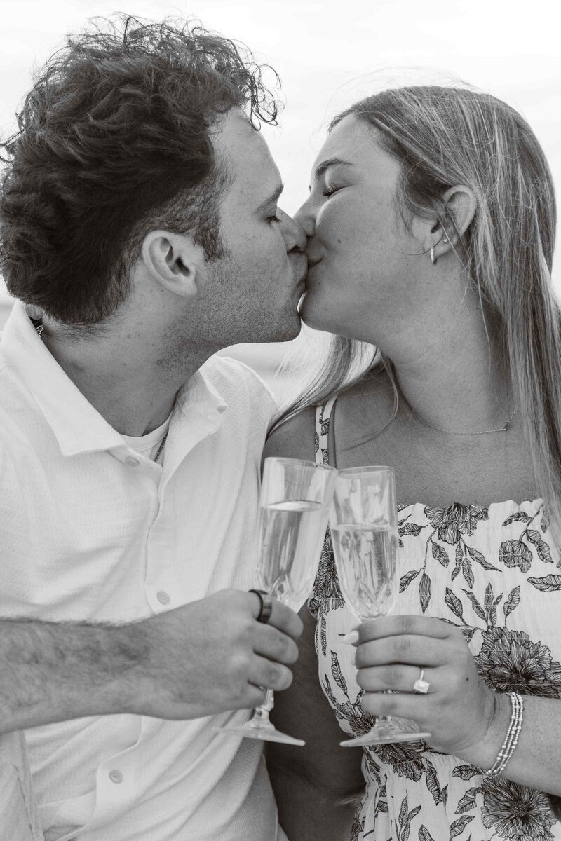 Man and woman kiss over champagne toast