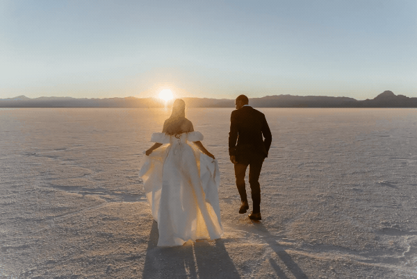 bride and groom running through sand dunes