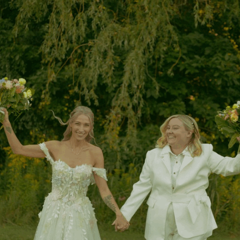 A woman holds her dress and lets it freely get caught in the wind while running through the forest
