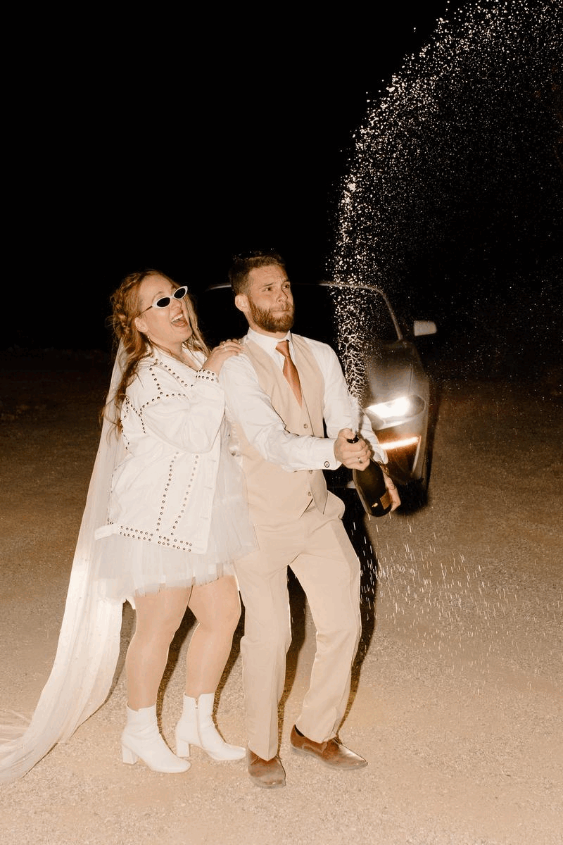 man and woman popping champagne with flash photos elopement in california