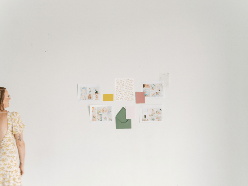 GIF of Jen Krause spinning in front of a collage of her stationery work on a white wall