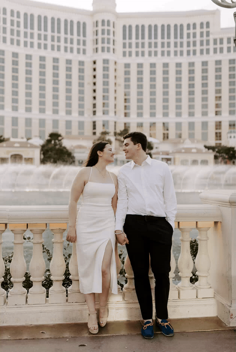 A couple holding hands and standing in front of a fountain 