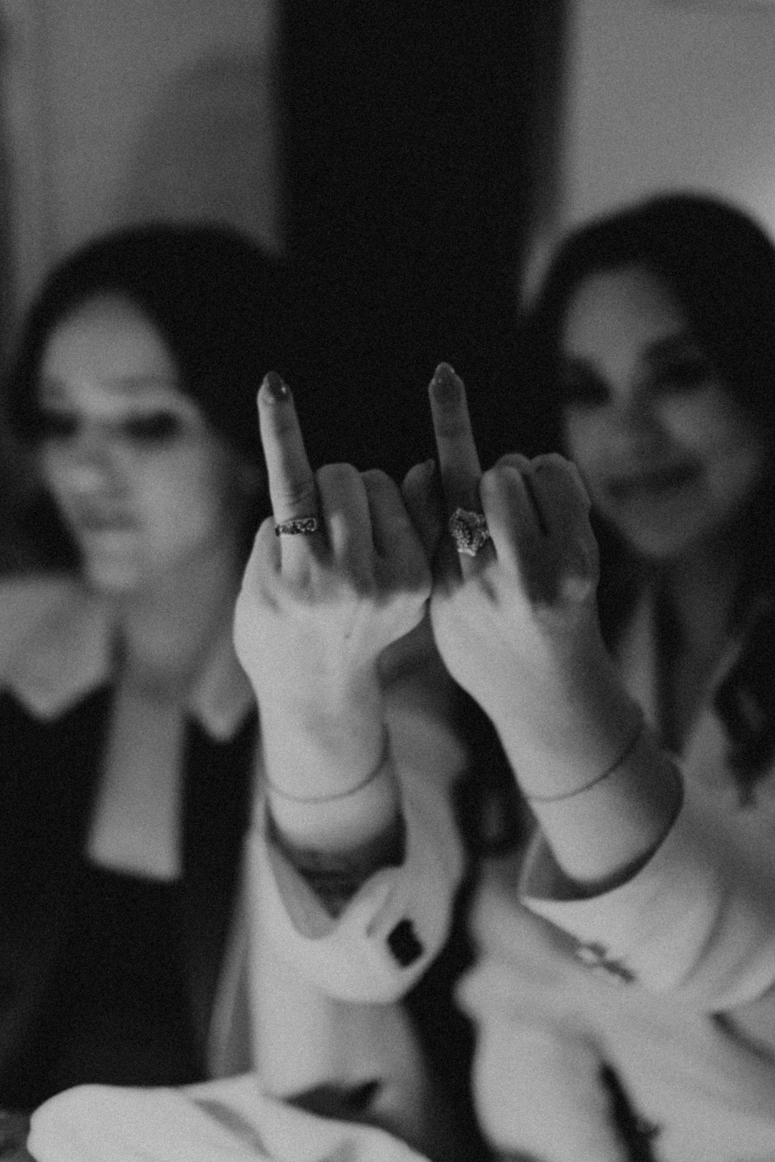Two women holding up their ring fingers, blurred in the background, celebrating together