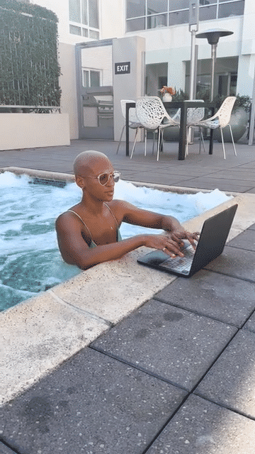 Gilleon Smith Mercado Lounging by Pool While Typing on Computer