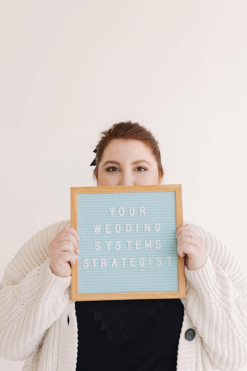 GIF of woman making silly faces and holding a sign that reads: your wedding systems strategist
