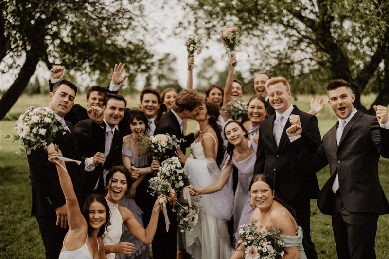 GIF of bride and groom kissing with wedding party cheering