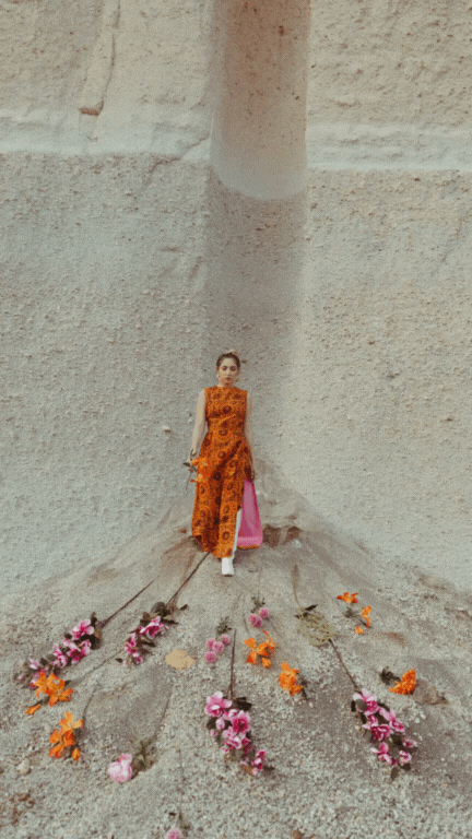 woman wearing an orange dress walking down a sand mountain