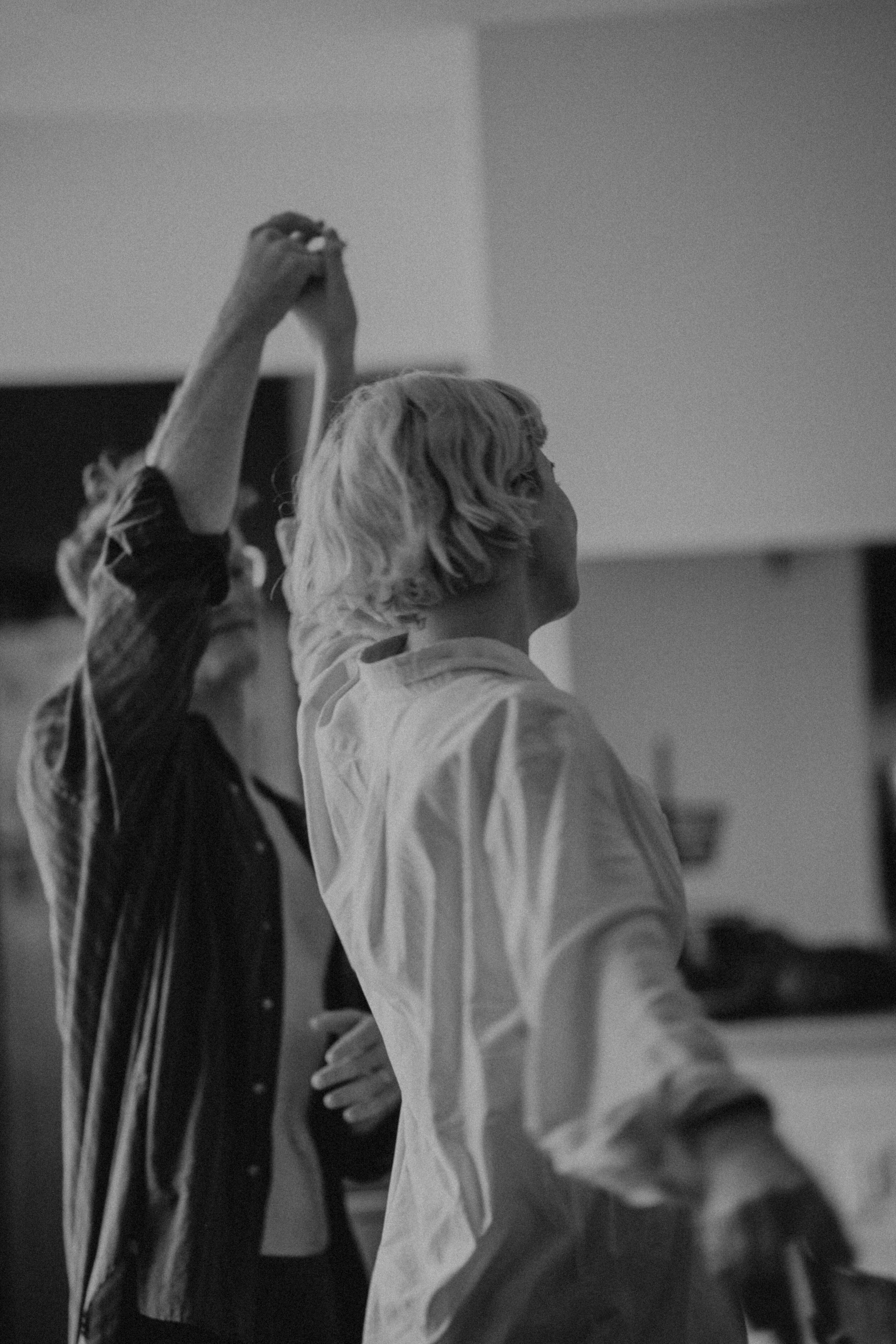 Couple dancing together indoors, captured from behind in black and white