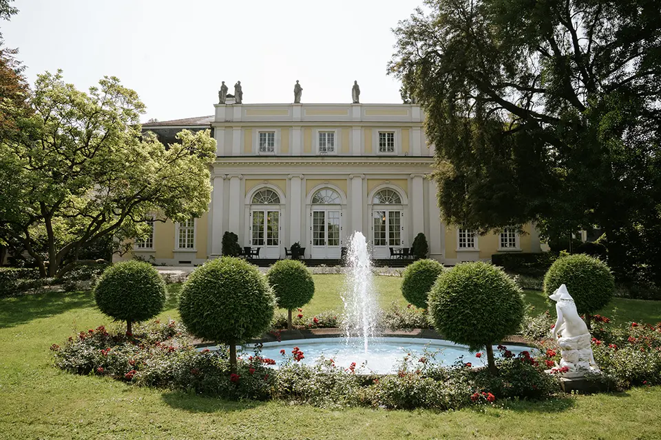 Historisches Palais mit Springbrunnen, umrahmt von Buchs und Rosen – ideale Kulisse für hochzeitsbilder draußen, natürliche hochzeitsfotografie und hochzeitsfotograf für schloss-hochzeit