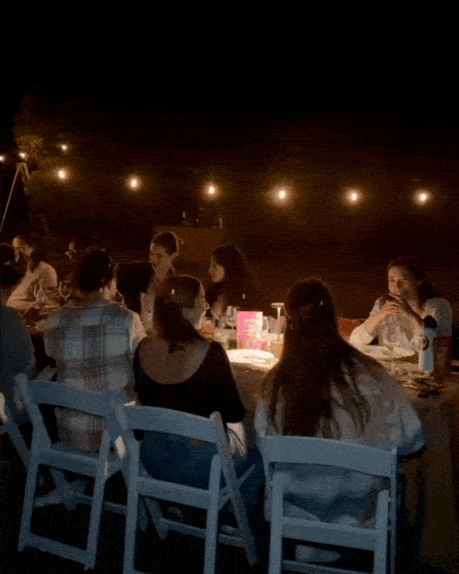 Guests enjoying a farm-to-table dinner outdoors around a table at night, sharing food and conversation at a Farm Dinner LA event